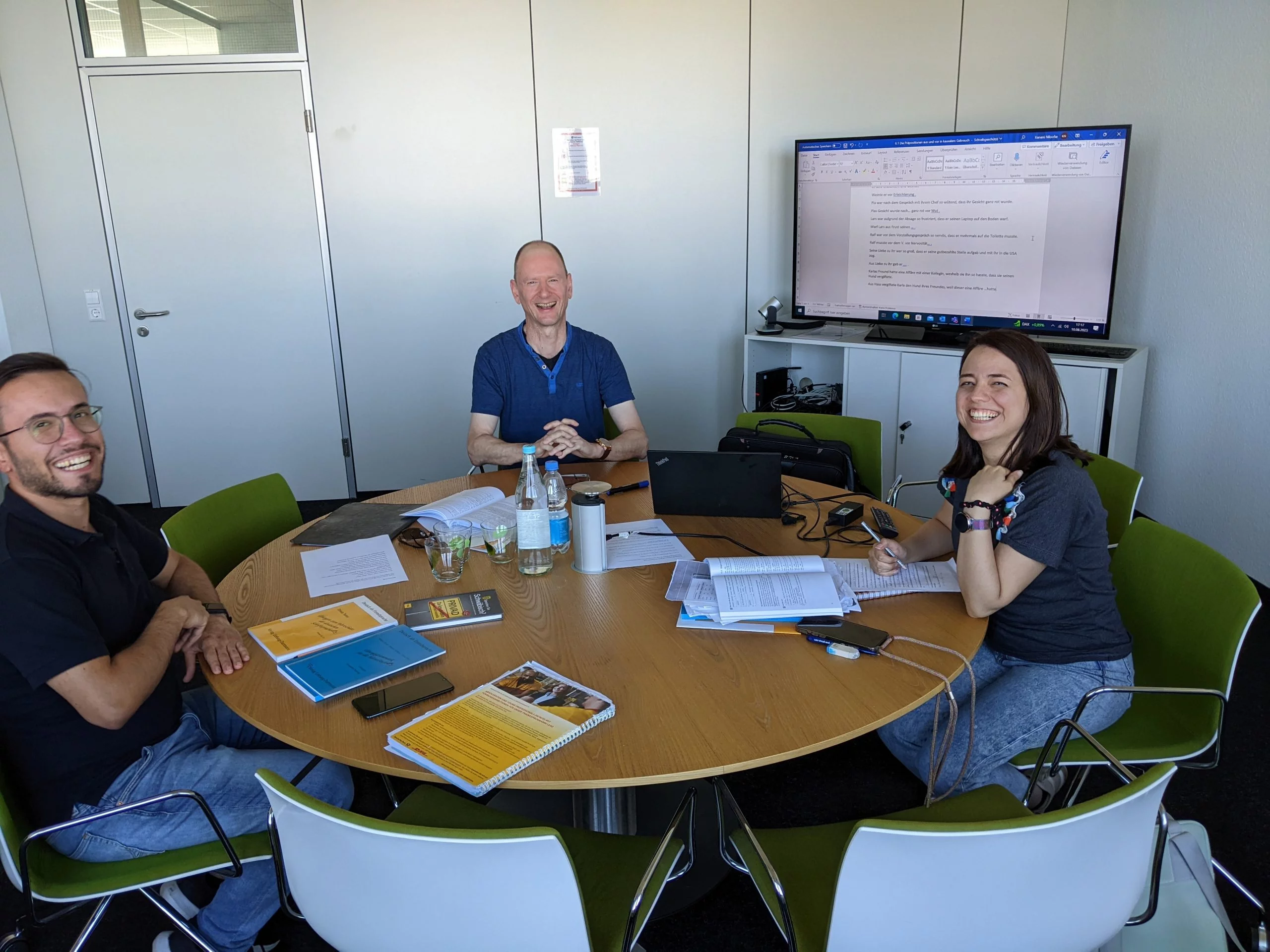 Language trainer conducting a face-to-face session with two employees around a round table in Stuttgart