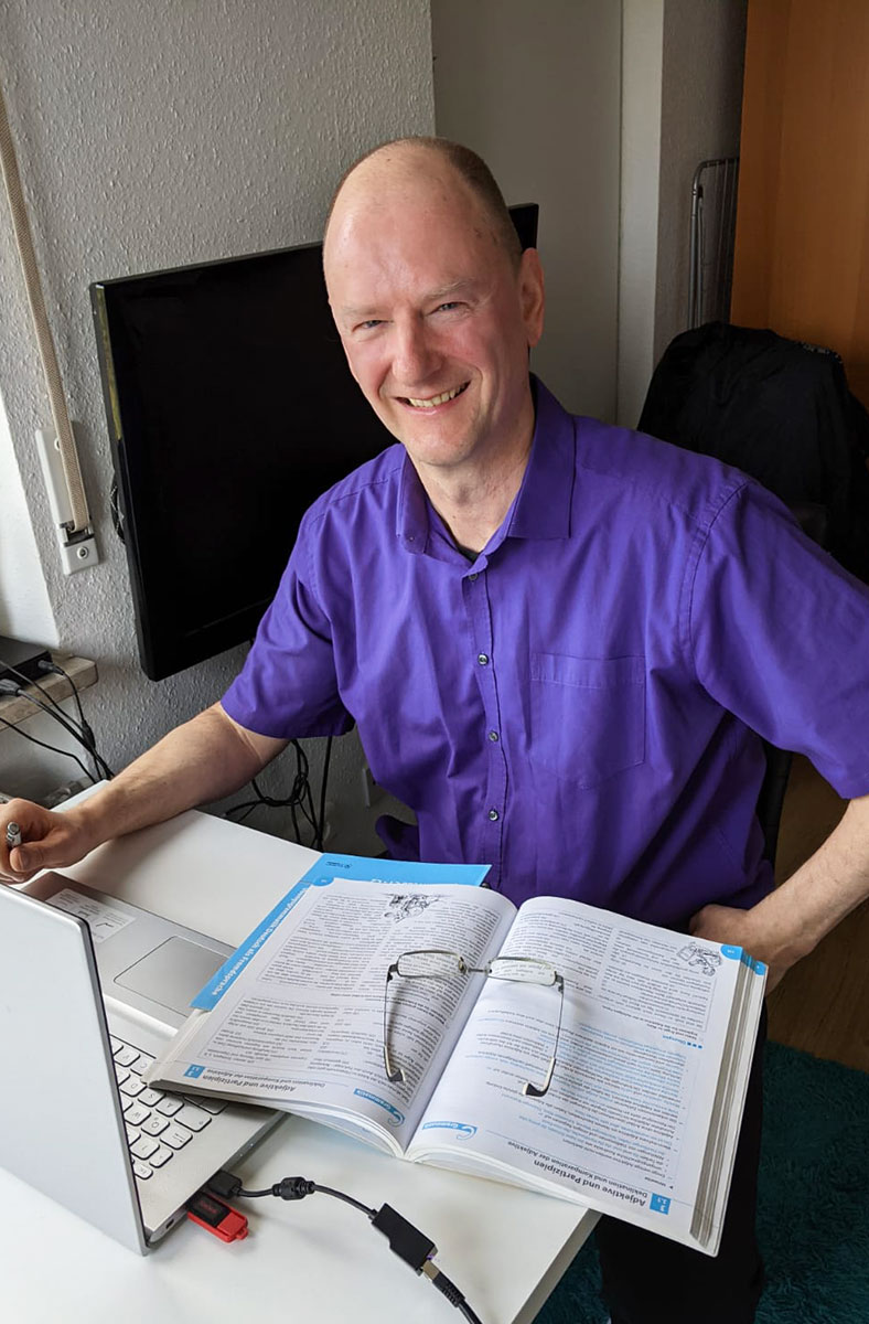 Rolf Schwedes, a german language coach for nonnative speaker sitting on a working table in a chair.