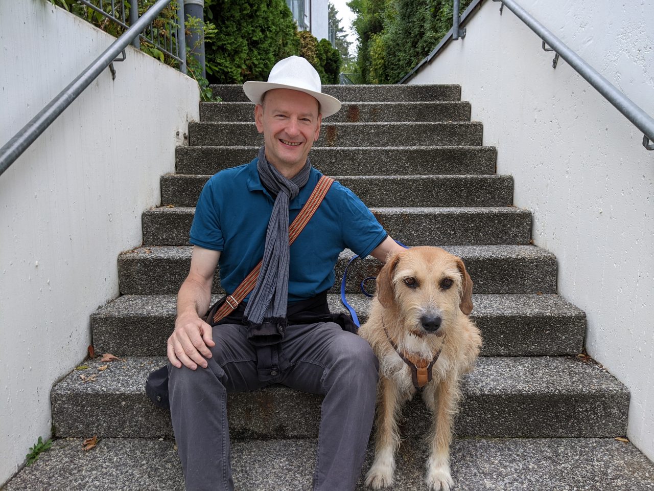 Der Sprachtrainer Rolf Schwedes sitzt draußen auf einer Treppe mit seiner Gassihündin 